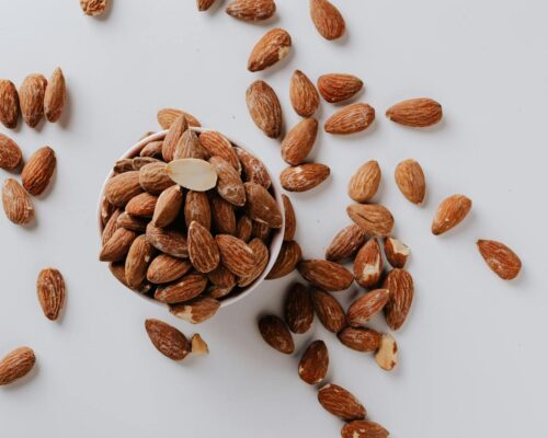 Bowl filled with raw almond nuts on white background