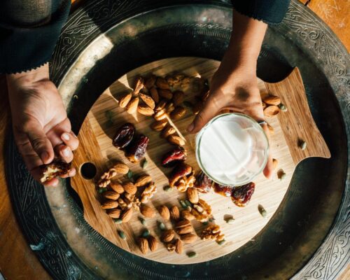 Person Holding a Glass of Milk and Palm Dates
